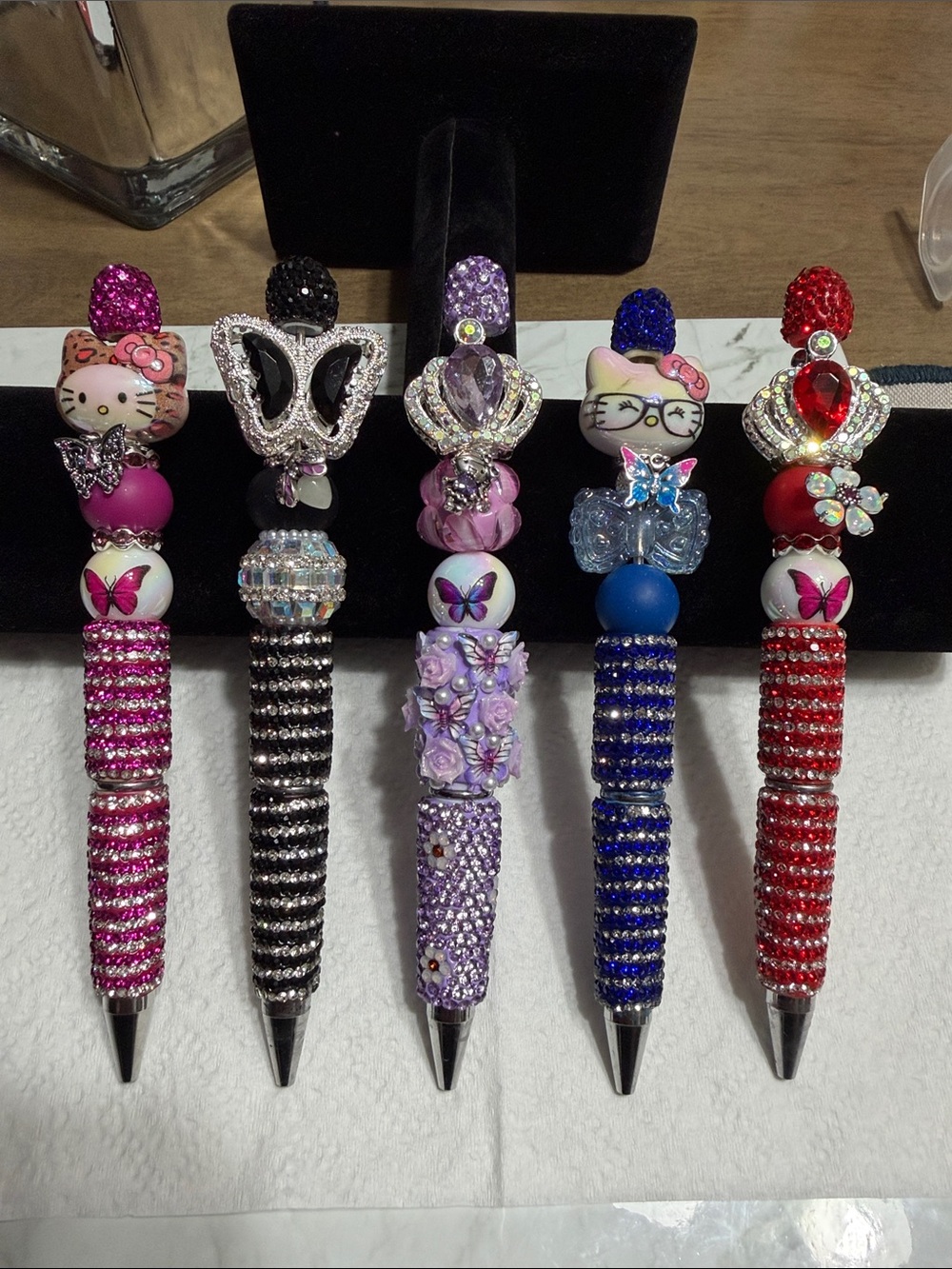 Five decorative bejeweled pens with charms and rhinestones.